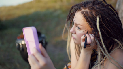 portrait of an attractive hippie woman with dreadlocks in the woods at sunset having good time outdoors