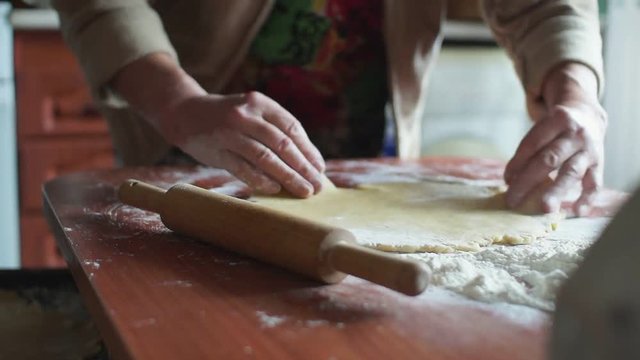 Woman kneading dough in flour on table