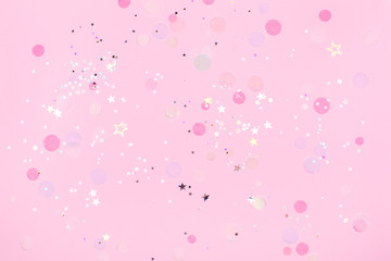 Pink pastel festive background with confetti and sparkles. Flat lay style.