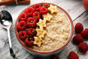 Bowl of oatmeal porridge with banana, raspberries coconut and caramel sauce on rustic table, hot and healthy food for Breakfast