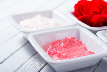 skin care creams and rose on white wooden table