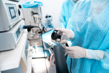 Professional doctor wearing blue medical clothes and rubber gloves while standing near the lithotripter