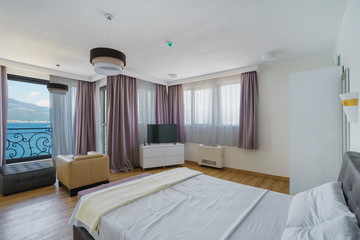 Interior of a spacious light bedroom with sea view in a luxury villa. Big comfortable double bed in elegant modern bedroom
