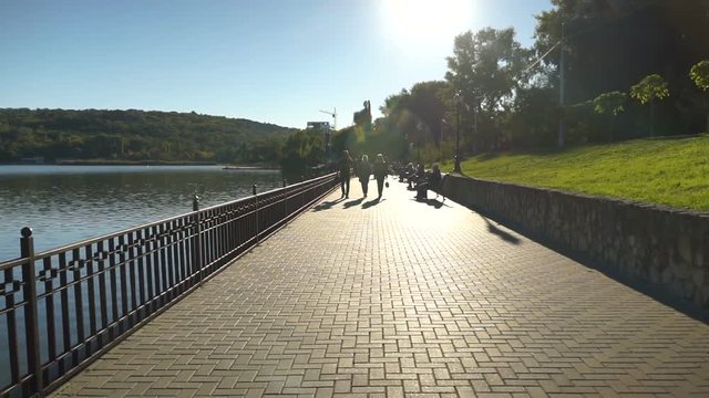 Blurred people walking on a pier on a sunny day. Steadicam shot.