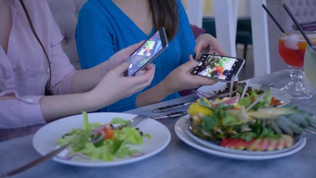 food photo on smartphone, bloggers girls take pictures of beautiful useful eating on cell phone during brunch during diet for weight loss in cafe close-up