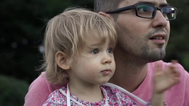 Young father and his little daughter are looking into the distance and waving their hands and sending kisses