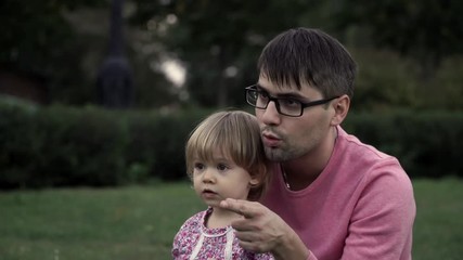 Young father and his little daughter are looking into the distance and waving goodbye