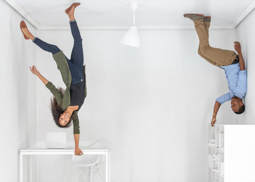 A young couple hanging upside down in an office