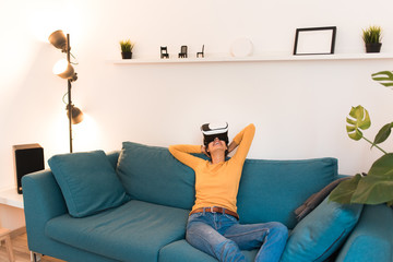 Young woman relaxing on the couch with virtual reality glasses. Fun with virtual reality headset. 
