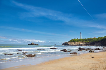 Biarritz, France. Sand beach, lighthouse, rocky shore of the ocean.  Bay of Biscay, Atlantic coast, Basque country. Sunny summer day with blue sky.