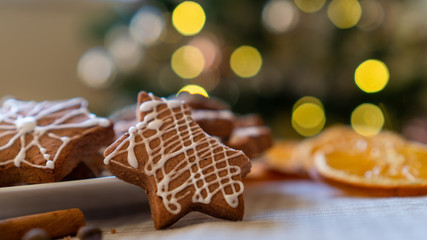 Blurred Christmas decor with fairy lights and selective focus on a gingerbread cookie. Winter Holiday concept.
