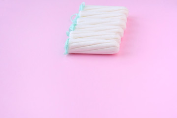 Row of six white tampons with selective focus and empty space for text on blurred pink background. Woman hygiene for period days, menstrual mothly cycle. Protective care for woman health.