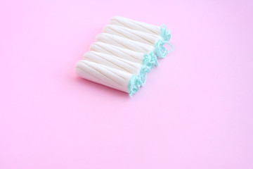 Row of six white tampons with selective focus and empty space for text on blurred pink background. Woman hygiene for period days, menstrual mothly cycle. Protective care for woman health.