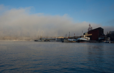 Foggy morning in stockholm harbour, ships and boats in the frosty mist and winter light