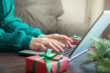 Christmas sales. Woman typing on laptop in home interior. Xmas concept. Planing holidays.
