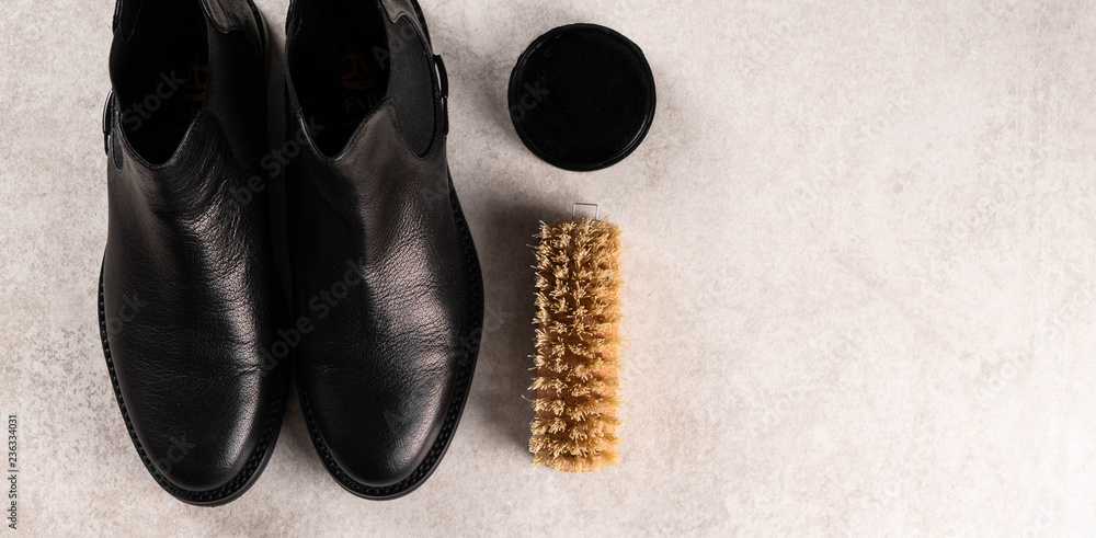 Wall mural black leather boots, shoe polish and a brush on light marble surface