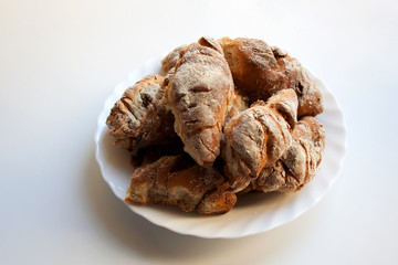 Freshly baked homemade croissants on plate isolated on white background