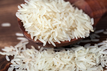 White jasmine rice in wooden spoon on dark table background