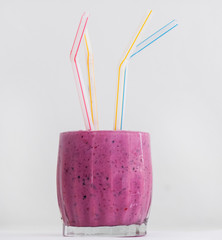 A mixed berry shake with natural yogurt and soy milk is shown in a glass with coloured plastic straws