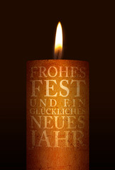 Weihnachtsmotiv einer brennenden Kerze auf dunklem Hintergrund