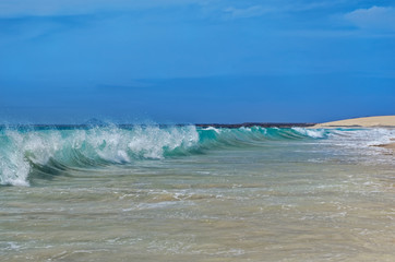 Turquoise colored waves crashing on the sandy beach in island of Sal, Cape Verde