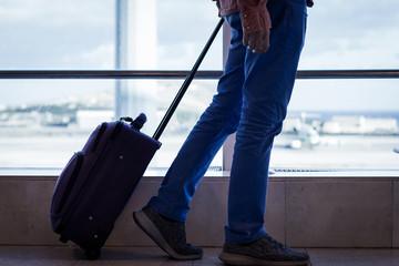 Man walking with carry on luggage at Las Palmas airport terminal. Airplane on landing area as...