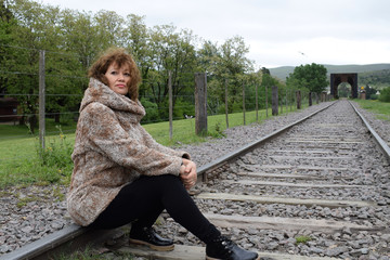 portrait of pretty woman resting on the railroad tracks in the afternoon