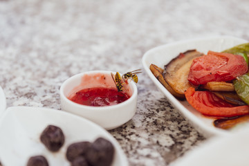 Two wasps eating jam on a breakfast table.   two bees eating marmalade. 