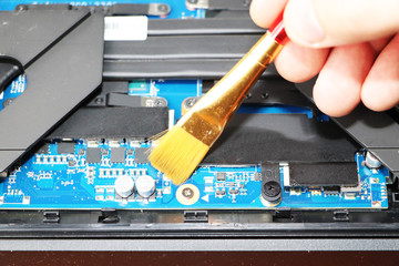 A geek cleans a laptop cooler. Contaminated computer cooling system. Technical support concept