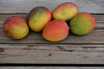 Group of ripe mangos on wooden surface