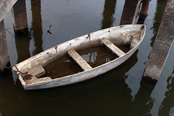 white old leaky boat half in the water on the river
