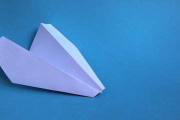 white paper plane lying on its side on a blue background
