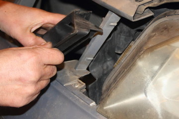 Men's rough hand disassembling plastic cover nesr car headlight - repair of vehicles, disassembling