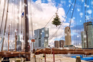 Foto auf Alu-Dibond Christmas cityscape - view of the skyscrapers of district Feijenoord through the rigging of the moored sailboat with Christmas tree, Rotterdam, Netherlands, December, 2017 © rustamank