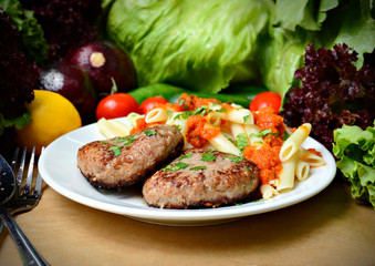 delicious cutlets with pasta and gravy, on the background of vegetables