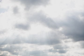 Sun hiding behind the fluffy clouds. Sunlight coming through clouds