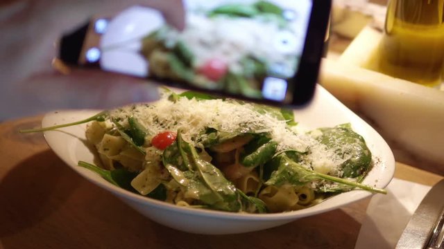 Woman taking photos of pasta dish by smartphone in 4k slow motion 60fps