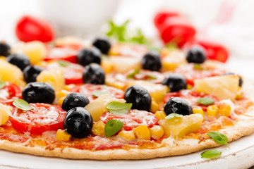 Pizza with tomatoes, mozzarella cheese, olives, corn and basil. Traditional italian cuisine