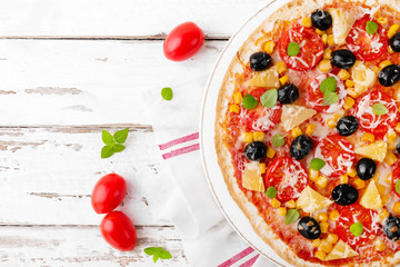 Pizza with tomatoes, mozzarella cheese, olives, corn and basil. Traditional italian cuisine. Top view