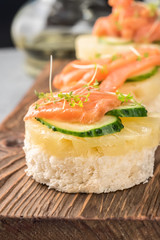 Bruschetta toast of white bread with slices of pineapple cucumber fish salmon fresh green sprouts