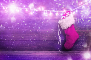Pink Santa stocking with gift boxes on wooden background.