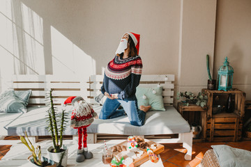 .Sweet and cheerful woman enjoying christmas at her home. Wearing christmas costume as Santa Claus. Having fun. Lifestyle. Season photography.
