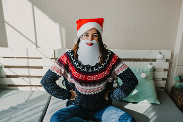 .Sweet and cheerful woman enjoying christmas at her home. Wearing christmas costume as Santa Claus. Having fun. Lifestyle. Season photography.