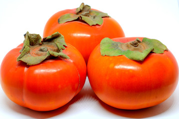 Three ripe juicy fruit persimmons orange on white background