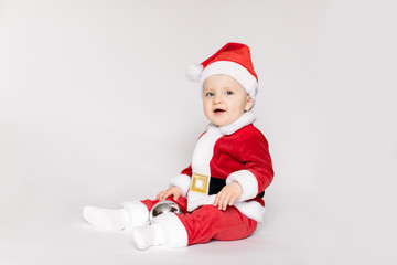 Very cute Caucasian little toddler baby wearing Santa costume with Christmas on the white background. Boy is laughing at the camera. Christmas concept.
