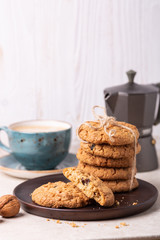 Cup of coffee, oatmeal cookies, coffee maker on white wooden background. Bright morning
