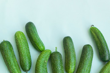 Fresh and sliced cucumbers on light blue background