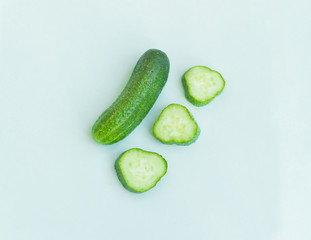 Fresh and sliced cucumbers on light blue background