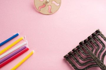 Image of jewish holiday Hanukkah with wooden dreidels (spinning top) , menorah (traditional Candelabra), candles, children's stickers glitter craft on pink background.Top view.Copy space for your text