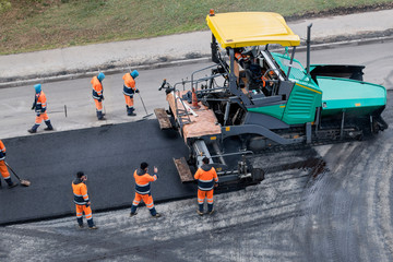 Asphalt paver machine or paver finisher  places a layer of fresh asphalt. Road renewal process, construction working. Collage, unrecognizable workers. High angle view.